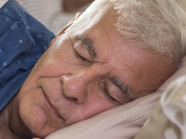 Un vieil homme dort dans un lit