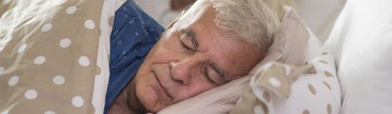 Un vieil homme dort dans un lit